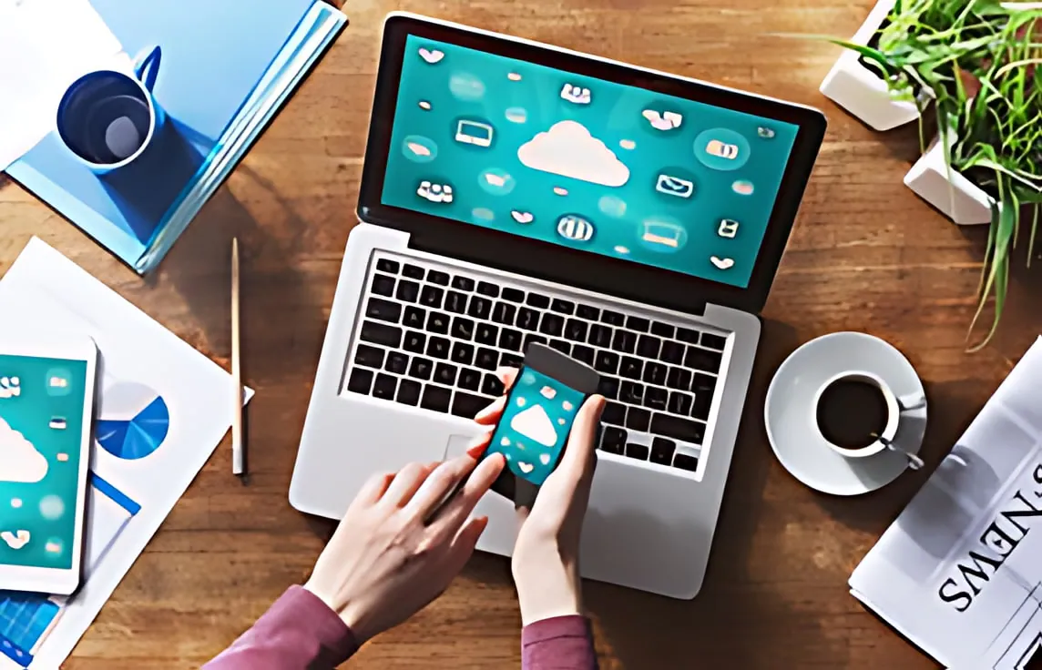 Espace de travail avec laptop et smartphone affichant des icônes cloud, représentant les services informatiques et cloud