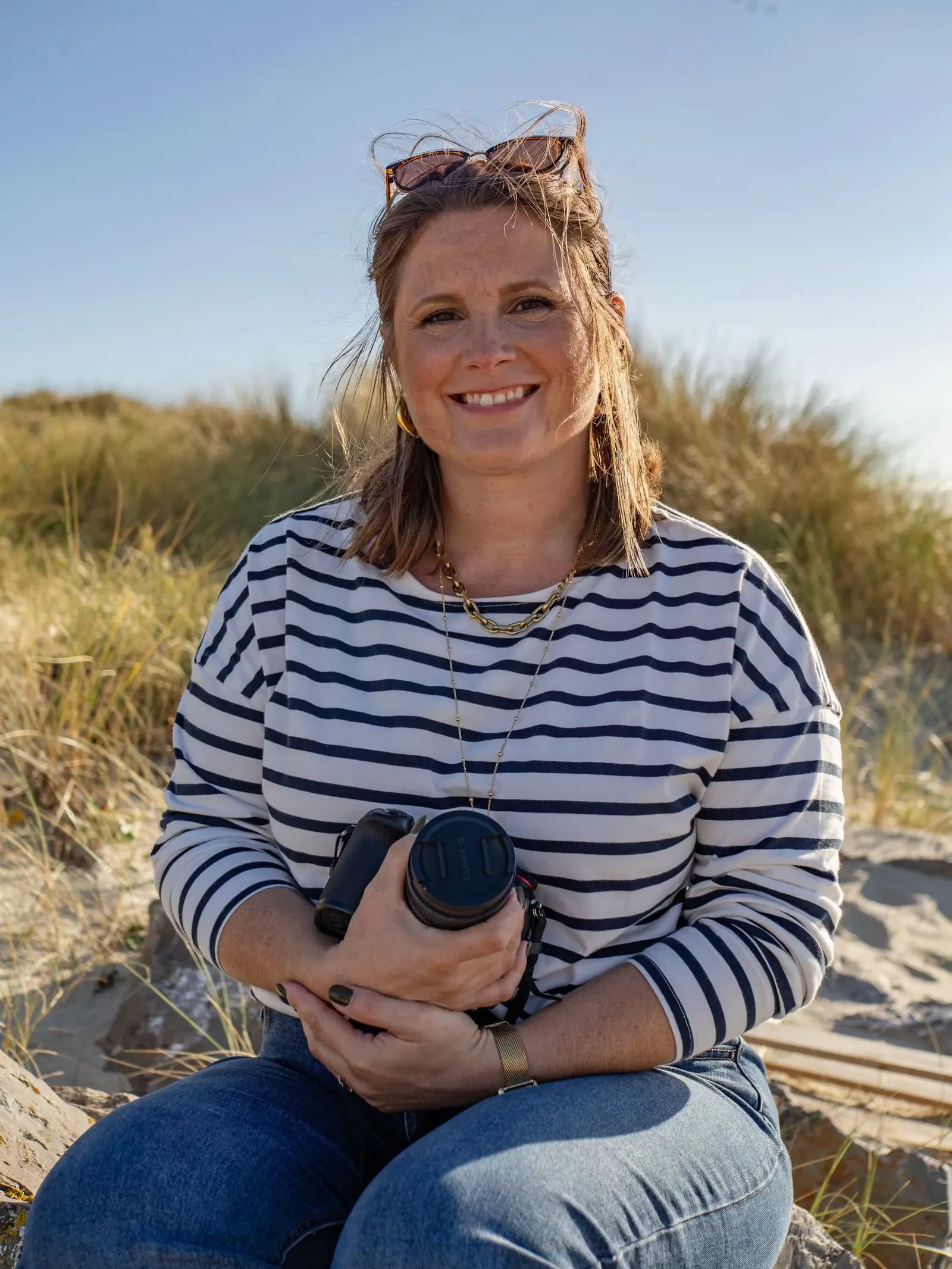 Femme souriante sur une plage de la Côte d'Opale tenant des jumelles